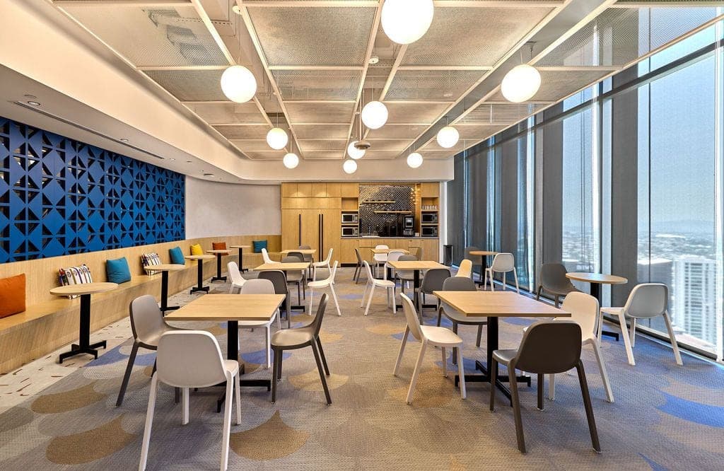 Comedor corporativo con muro azul geométrico y péndulos globo